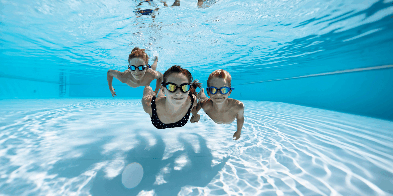 Trois enfants jouant dans une piscine où une fuite sur la bonde de fond est possible