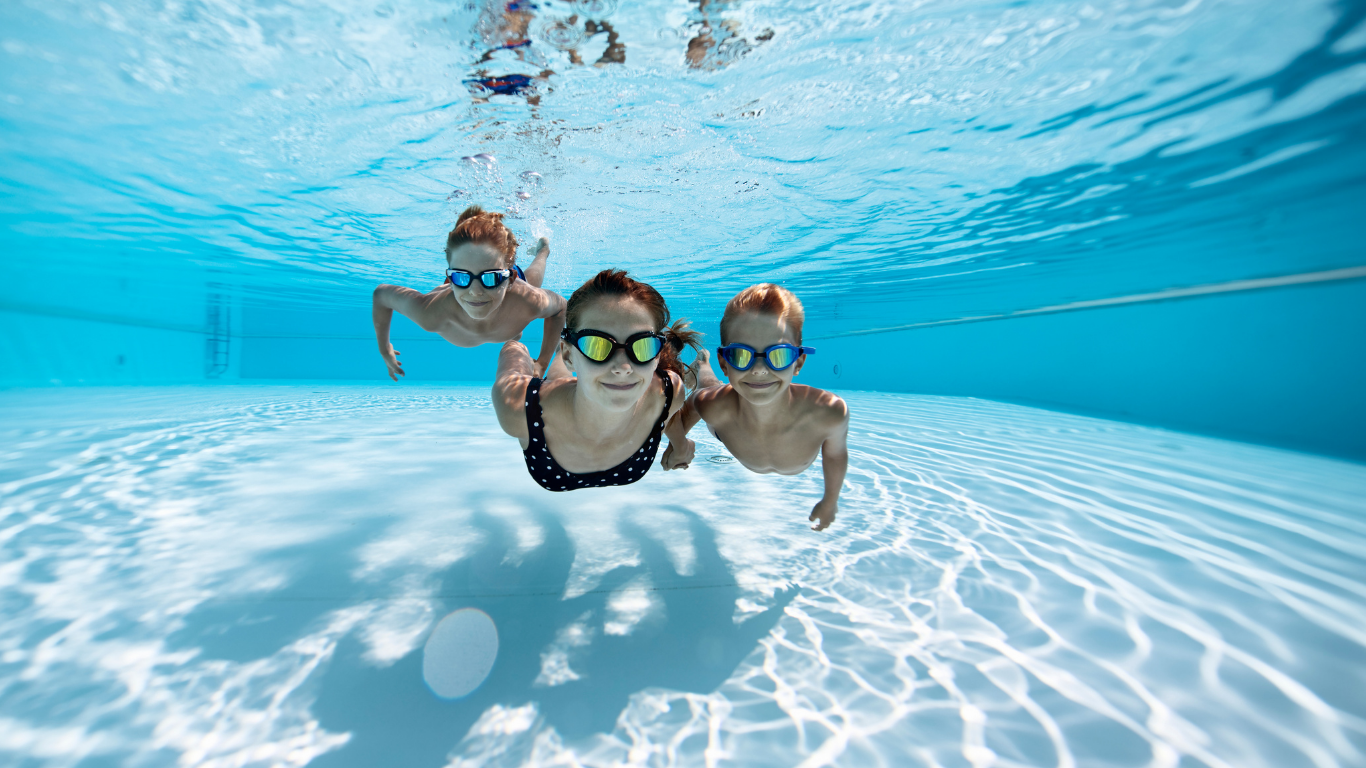 Trois enfants jouant dans une piscine où une fuite sur la bonde de fond est possible