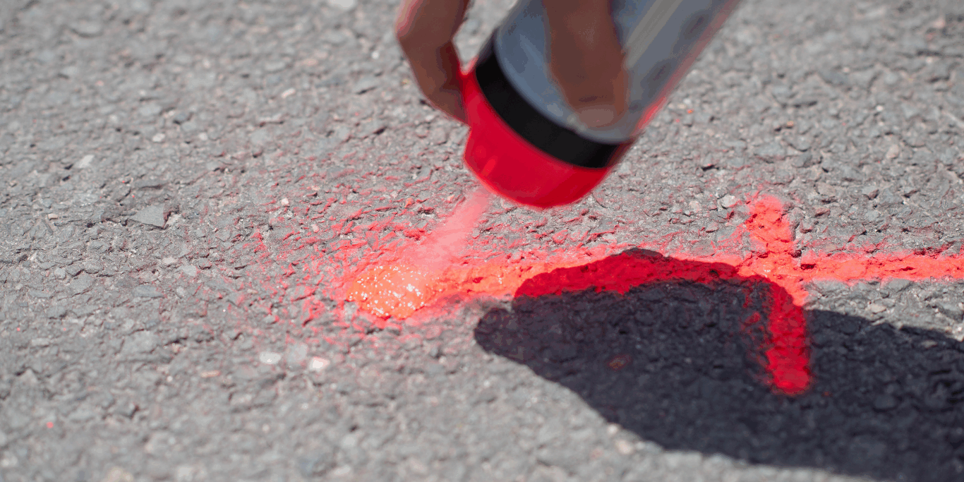 Marquage au sol rouge en spray pour détection regard télécom sur chaussée.