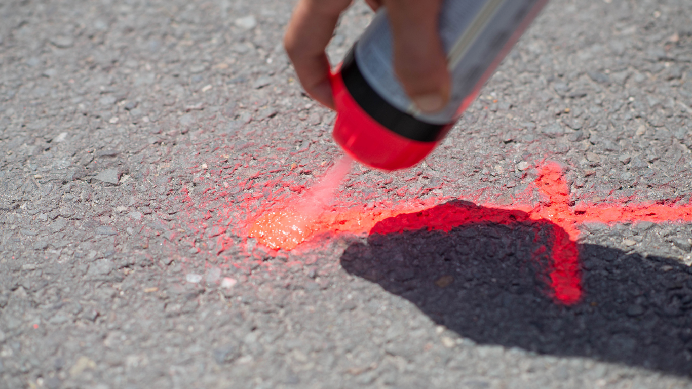 Marquage au sol rouge en spray pour détection regard télécom sur chaussée.